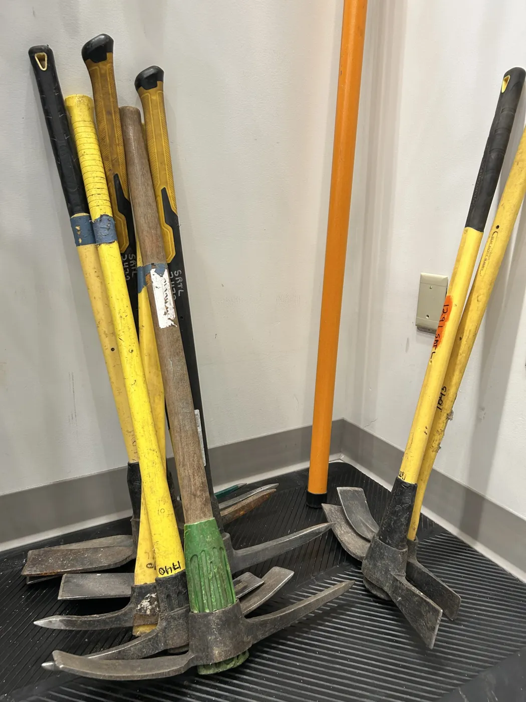 Sledgehammers and pickaxes leaning against a wall