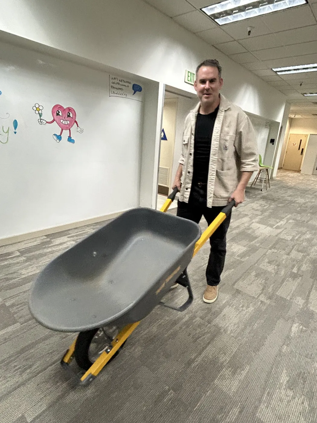 Member wheeling a borrowed wheelbarrow down the hallway
