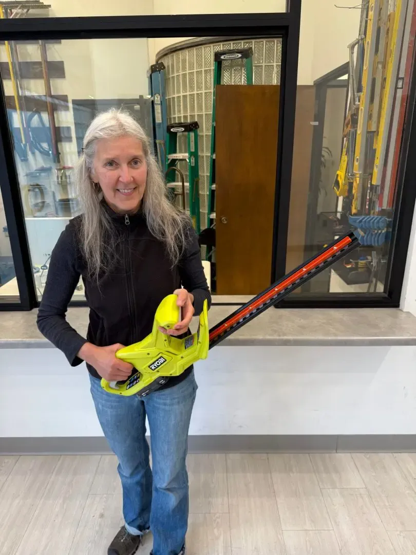Volunteer holding a cordless hedge trimmer